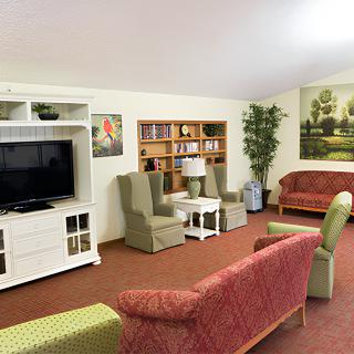 A cozy living room with a television, sofas, armchairs, and a bookshelf.