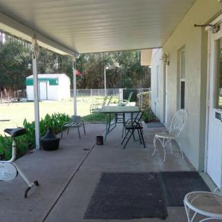 A covered patio with outdoor furniture and potted plants overlooking a backyard.
