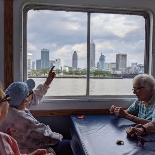 A group of seniors enjoy a scenic city skyline view from a boat window.