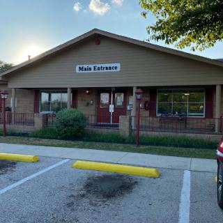 Facade of a restaurant with clear signage and parked cars.