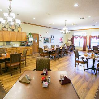 A cozy dining room with wooden floors and neatly arranged tables and chairs.