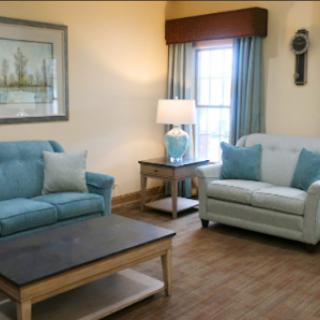 A cozy living room featuring light blue and white furniture, complemented by natural light and decorative accents.