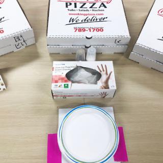 A collection of pizza boxes alongside a takeout container and a plate, ready for a meal.