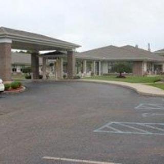 An exterior view of a residential facility with a welcoming entrance and parking area.