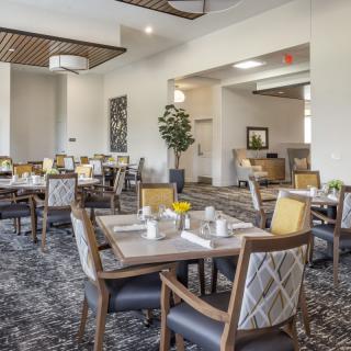 A modern dining area with neatly arranged tables and chairs, featuring stylish interior design and comfortable seating.