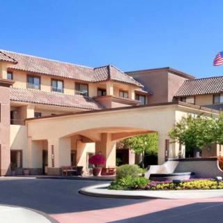 The front entrance of a hotel with landscaped surroundings and an American flag.