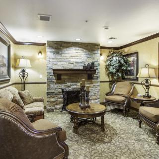 A cozy living room with a stone fireplace, traditional furniture, and warm lighting.
