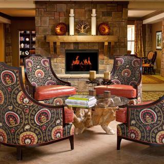 A cozy living room with patterned armchairs arranged around a fireplace, creating a warm and inviting atmosphere.