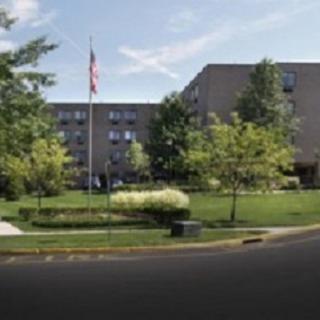 A view of a multi-story building surrounded by greenery and an American flag.