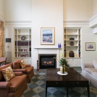 A cozy living room featuring a fireplace, shelves filled with decor, and comfortable seating including armchairs and a sofa.