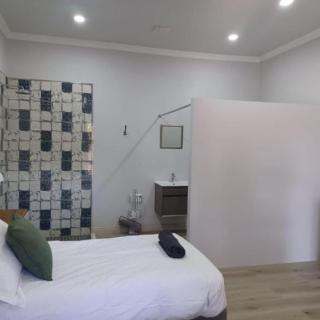 A modern, minimalist bedroom featuring a single bed with white linens and a decorative tiled wall.