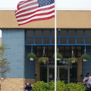 A flag waving in front of a modern building entrance.