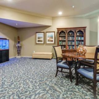 A cozy living room with a table and chairs set, an aquarium, and a large bookshelf.
