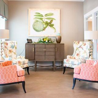 A cozy living room with floral armchairs, a sideboard, and decorative artwork.