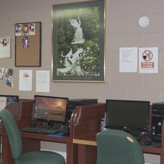 A computer lab with several desks and computers, decorated with posters and wall art.