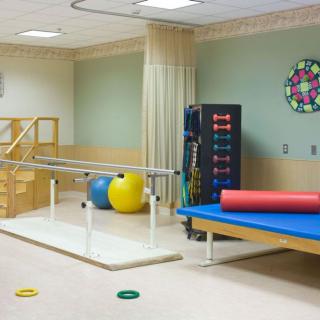 A physical therapy room equipped with parallel bars and exercise equipment.
