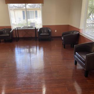 An empty waiting room with leather chairs and hardwood floors.