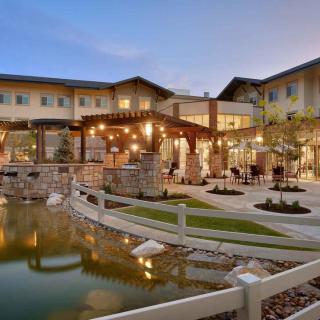 A beautifully lit building with a serene pond and landscaped outdoor area during the evening.
