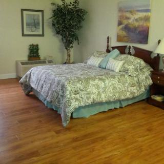 A cozy bedroom with a large bed, decorative pillows, hardwood flooring, and wall art.