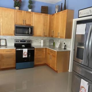 A modern kitchen with wooden cabinets, stainless steel appliances, and decorative plants.