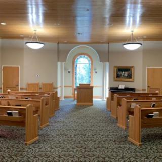 Interior view of a chapel with wooden pews and a central pulpit.