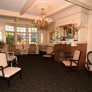 A classic living room with elegant furnishings, featuring a chandelier and large windows.