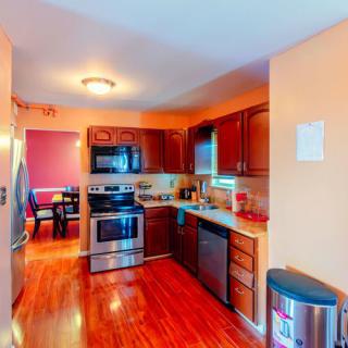 A modern kitchen with wooden floors and stainless steel appliances.