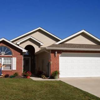 A charming single-family home with a well-maintained lawn and a clear blue sky.