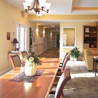 A well-lit dining area with a wooden table, chairs, a decorative chandelier, and floral centerpiece.