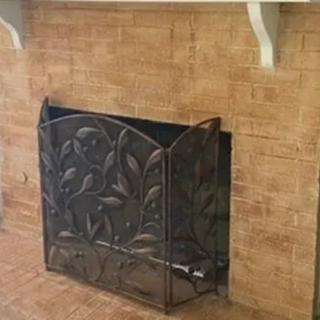 A decorative metal fireplace screen with a floral pattern.