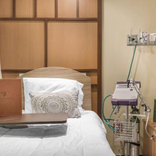 A well-equipped hospital patient room featuring a comfortable bed and essential medical devices.