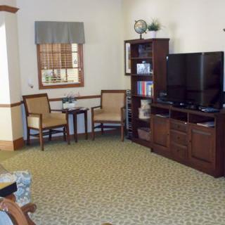 A cozy living room with a television, shelving unit, and seating area.