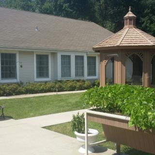 A sunny outdoor garden area with a small gazebo and adjacent building.