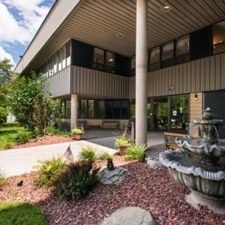 An office building with a landscaped garden and fountain in the foreground.