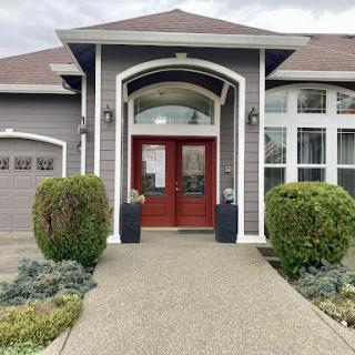 A modern home with a welcoming front entrance, featuring double doors and beautifully arranged landscaping.