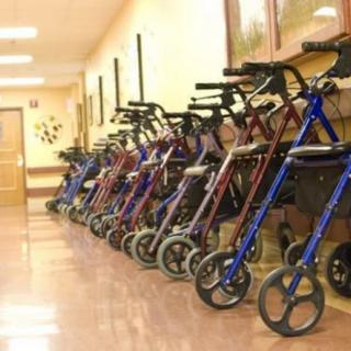 A row of walkers lined up in a hallway, typically found in an assisted living facility.