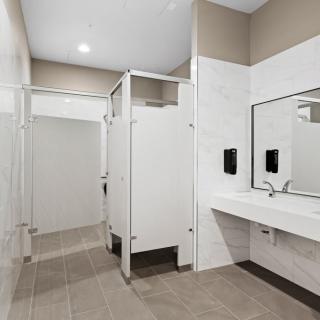 A clean and modern public restroom with stalls, sinks, and mirrors.