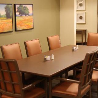 A neat conference room with a rectangular table surrounded by several chairs, adorned with artwork on the walls.