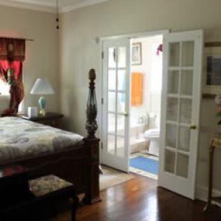 A cozy bedroom with a view into an adjoining bathroom through French doors.