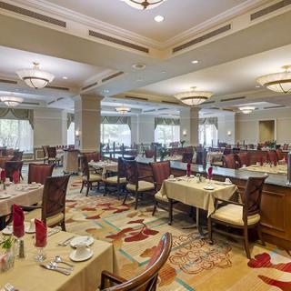 An elegant restaurant dining room with neatly arranged tables and chairs, adorned with sophisticated decor and soft lighting.