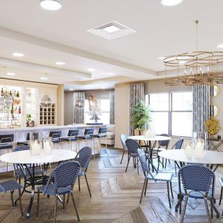 A modern dining area with a bar, round tables, and stylish chairs under bright lighting.
