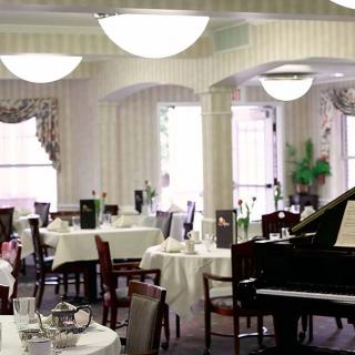 An elegant restaurant dining room with a piano and set tables.