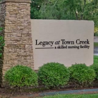 Sign for Legacy at Town Creek, a skilled nursing facility, surrounded by greenery.