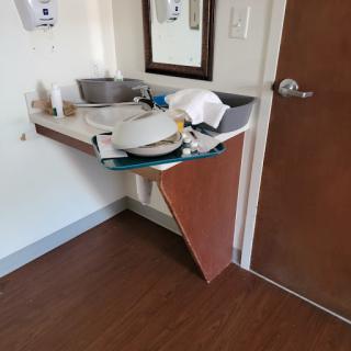 A bathroom area featuring a sink and various items on a cluttered countertop.