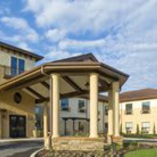 A residential building with a grand entrance supported by columns under a partly cloudy sky.