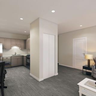 A modern apartment interior featuring an open kitchen and living room area with plush carpeting and contemporary furnishings.