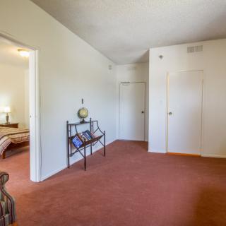 A cozy living room with carpeted flooring and simple furnishings.