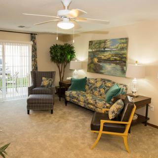 A cozy living room with a sofa, armchair, and accent chair, featuring warm lighting and decorative artwork.