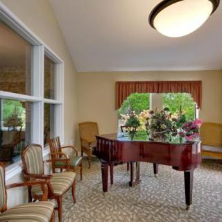 A cozy room with a grand piano, surrounded by elegant chairs and large windows.