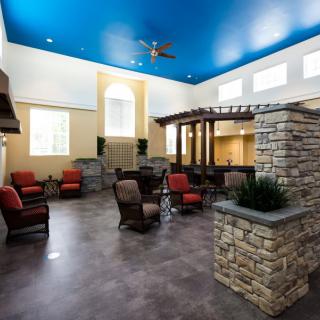 A modern lounge area with comfortable seating and stone accents under a bright blue ceiling.